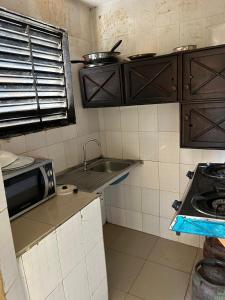 a small kitchen with a sink and a microwave at Room 11 in Kololi