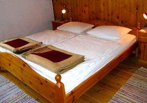 a large wooden bed with white sheets and pillows at Gästehaus Erlhof in Schiefling am See