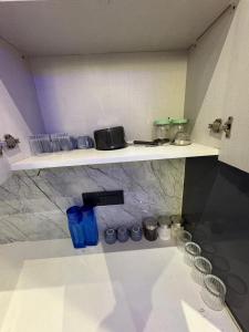 a kitchen with a counter with blue glasses on shelves at Hotel Namaste With Jacuzzi in Ghaziabad
