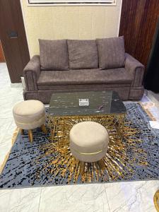 a living room with a couch and a table and two stools at Hotel Namaste With Jacuzzi in Ghaziabad