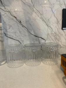 three clear glasses sitting on top of a counter at Hotel Namaste With Jacuzzi in Ghaziabad