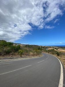 an empty road with the ocean in the background at le paradis vert bleu in Saint-Paul +4 photos