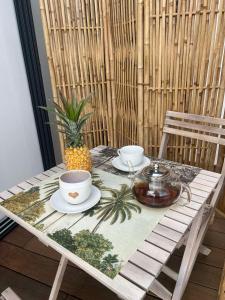 a table with two cups and plates and a pineapple on it at le paradis vert bleu in Saint-Paul