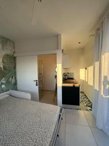 a bedroom with a bed and a small kitchen at le paradis vert bleu in Saint-Paul