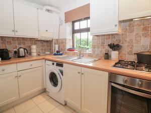 a kitchen with white cabinets and a washer and dryer at Win Hill View Cottage in Hope