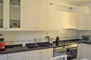 a kitchen with white cabinets and a stove and sink at Il Glicine in Làconi
