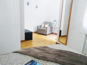 a bedroom with a mirror and a couch and a chair at La CASINA de HUGO con Terraza in Luanco