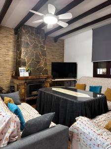 a living room with couches and a table and a tv at Chalet vacacional con piscina privada in Arriate