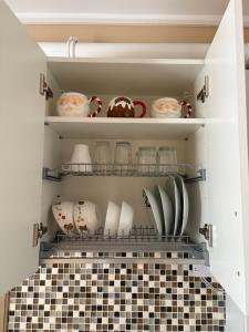 a cupboard with dishes and plates on a tiled floor at Studio Sunrise in Sinaia