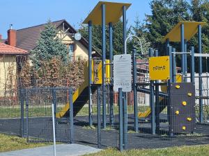 a playground with a yellow slide in a yard at Apartament Dobra Nocka 2 in Przeworsk