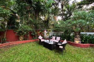 a garden with a couch and chairs in the grass at StayVista at Villa Arcadia with Alfresco Dining in Candolim