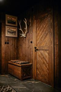 a room with a wooden door and a bench with a stag head at Na Gorczańskim Wierchu Chalet, basen, sauna, balia na wyłączność in Rabka-Zdrój +68 photos