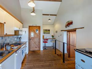 a kitchen with white cabinets and a wooden floor at 3 Bed in Bude oc-corym in Morwenstow