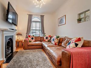 a living room with a brown leather couch and a fireplace at 3 Bed in Newquay oc-53688 in Newquay