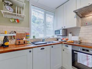 a kitchen with white cabinets and a sink and a window at 2 Bed in Looe oc-82537 in Looe