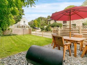 a patio with a table and a red umbrella at 2 Bed in St. Austell oc-82609 in St Austell