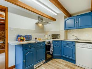 a blue kitchen with white appliances and blue cabinets at 2 Bed in St. Austell oc-82609 in St Austell
