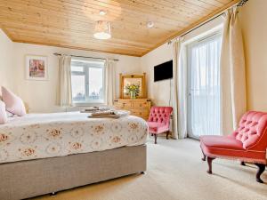 a bedroom with a bed and two red chairs at 3 Bed in Padstow oc-treba in Saint Merryn