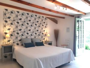 a bedroom with a white bed and a wall with flowers at Le Mas Cauvy in Saint-Christol-lès-Alès
