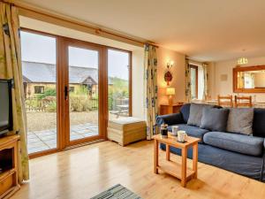 a living room with a blue couch and a sliding glass door at 3 Bed in Bridport oc-dc087 in Chideock