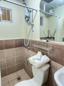 ein Badezimmer mit Toilette, Waschbecken und Spiegel in der Unterkunft Js Place at Arezzo Place Davao in Davao City + 12 Fotos