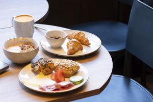 a table with two plates of pastries and a cup of coffee at Scandic Charlottenburg in Berlin +10 photos