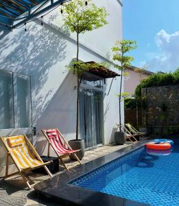 a swimming pool with two lawn chairs next to a house at Fullhouse Hoian in Hoi An