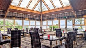a dining room with tables and chairs and windows at Garden Room Lodges in Alexandria