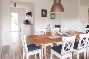 a dining room with a wooden table and white chairs at Bootshaus in Timmendorfer Strand
