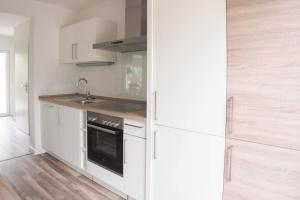 a white kitchen with a sink and a refrigerator at Bootshaus in Timmendorfer Strand +19 photos