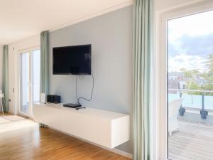 a white living room with a tv on a wall at Loft in Timmendorfer Strand