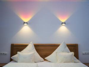two lights above a bed with white sheets and pillows at Ferienweingut-Liebfried in Nehren