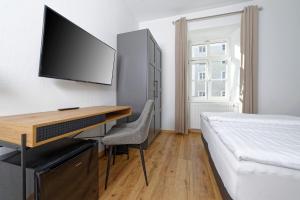 a bedroom with a desk with a tv and a bed at Boardinghouse Rosenheim in Rosenheim