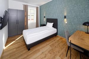 a bedroom with a bed and a table and a desk at Boardinghouse Rosenheim in Rosenheim +3 photos