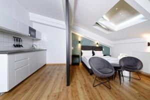 a kitchen and a bedroom with a bed and two chairs at Boardinghouse Rosenheim in Rosenheim