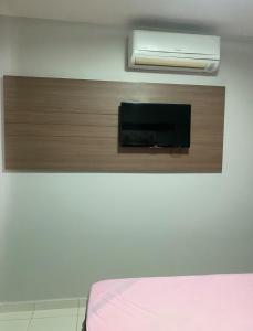 a room with a wall with a tv and a bed at Flat veredas 300 metros HOT PARK com ar na sala in Rio Quente