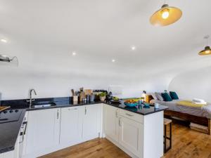 a kitchen with white cabinets and a bed in the background at 1 Bed in Bude oc-88498 in Morwenstow