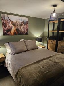 a bedroom with a bed with a painting of a bull at Veenemaat B&B in Winterswijk