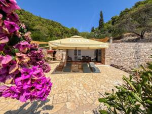 a patio with a tan umbrella and purple flowers at Robinson Apollon in Gdinj