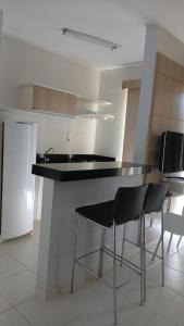 a kitchen with a counter with two chairs and a refrigerator at Flat veredas 300 metros HOT PARK com ar na sala in Rio Quente