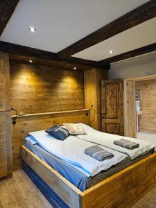a large bed in a room with wooden walls at Alleghe Lodge in Masarè