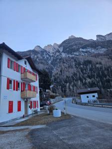 a white building with red windows and a mountain at Alleghe Lodge in Masarè