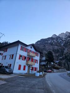 a white building with red windows on the side of a road at Alleghe Lodge in Masarè +21 photos