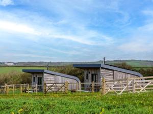 two wooden buildings in a field with a fence at 1 Bed in Bude oc-88499 in Morwenstow