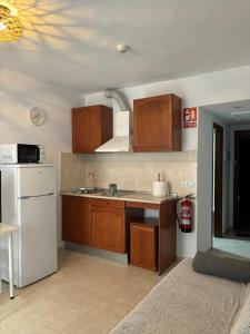a kitchen with wooden cabinets and a white refrigerator at Apartamento Amy 4 in Huelva