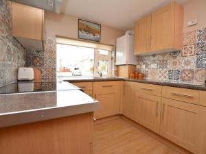 a large kitchen with wooden cabinets and a window at 1 Bed in Wadebridge oc-42756 in Wadebridge