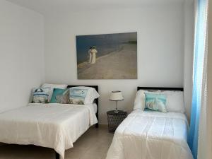 a bedroom with two beds and a painting on the wall at Apartamento Amy 4 in Huelva