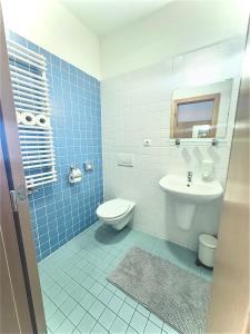 a blue tiled bathroom with a toilet and a sink at Hotel Ledňáček in Ostrava