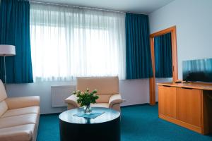 a hotel room with a couch and a table with a television at Hotel Ledňáček in Ostrava