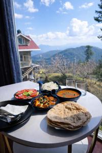 a table with plates of food on it with a view at White Castle Himalayan View by Lavender Hotels in Shimla